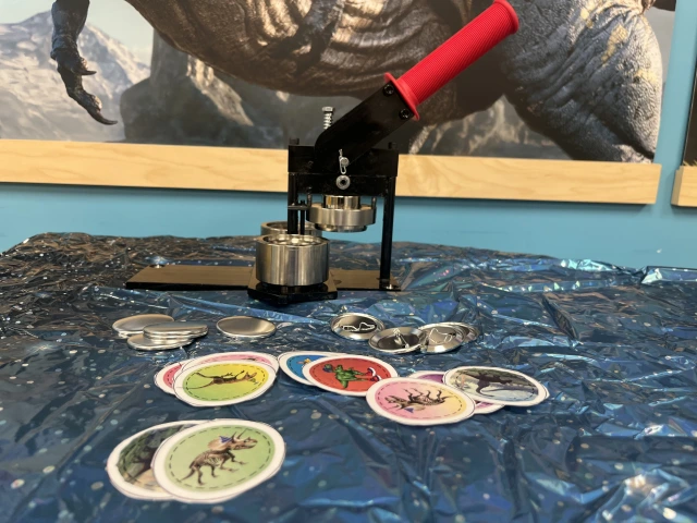 A button machine with dinosaur images and other button making materials