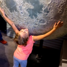 Little girl hugs small replica of moon